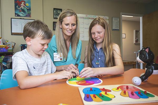 applied behavior analysis student working with two children at a table