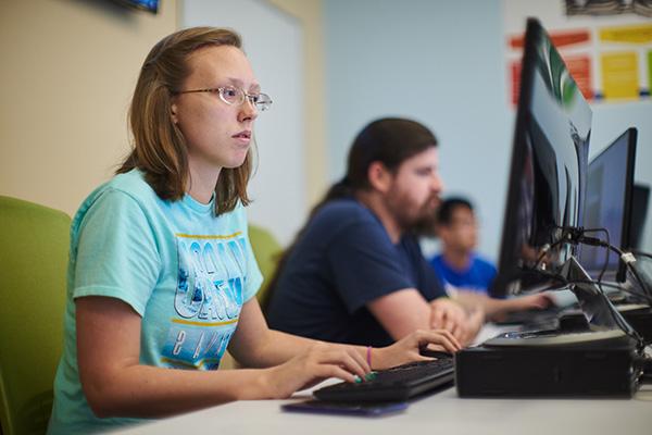 three software design students practicing programming in a computer lab